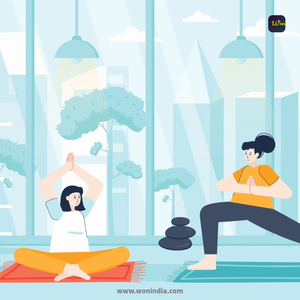 Two women practicing yoga indoors in a bright, airy space with large windows. One woman sits cross-legged on a red mat with her hands raised in a meditative pose, while the other stands in a warrior pose on a blue mat, hands in prayer position. A stack of black stones is placed nearby, and greenery can be seen outside the windows, enhancing the calming atmosphere.